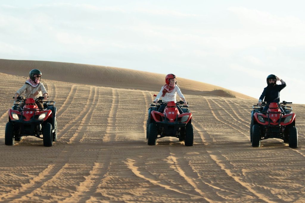 Three riders on quad bikes on sand dunes