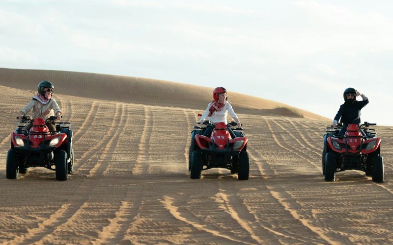 Three riders on quad bikes on sand dunes